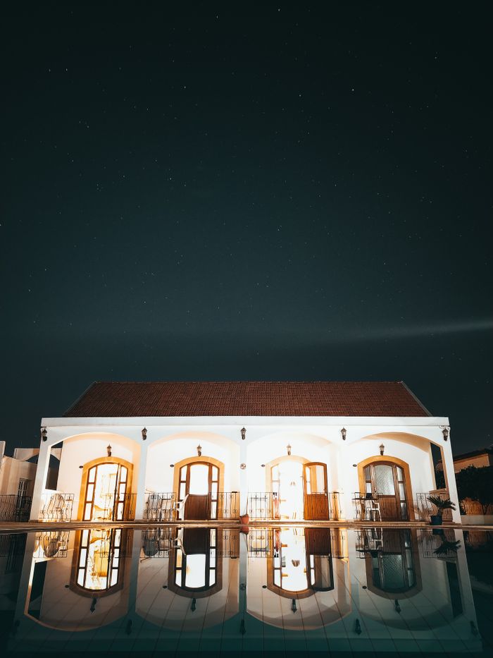 Beautiful villa reflected in pool under a clear, starry night sky.
