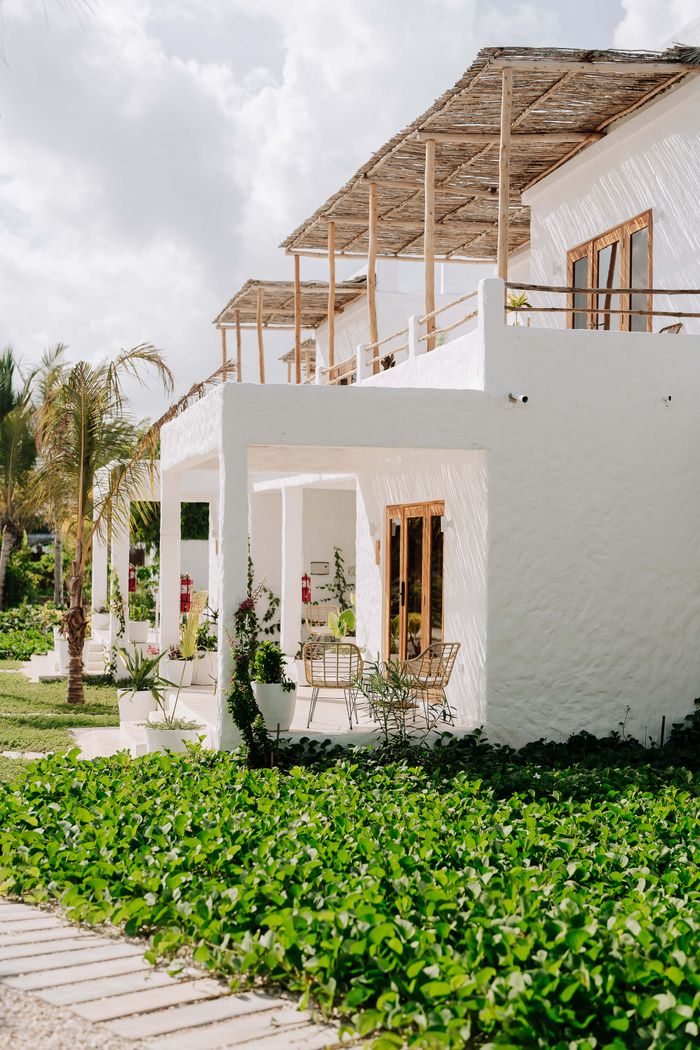 about-us Charming white villas with outdoor seating, surrounded by vibrant greenery in Jambiani, Tanzania.