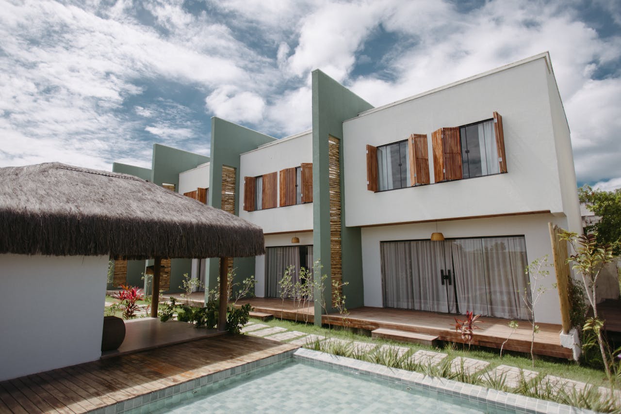 who-we-are Stylish modern villas with wooden accents and thatched roofing by a pool under a vibrant sky in Bahia, Brazil.